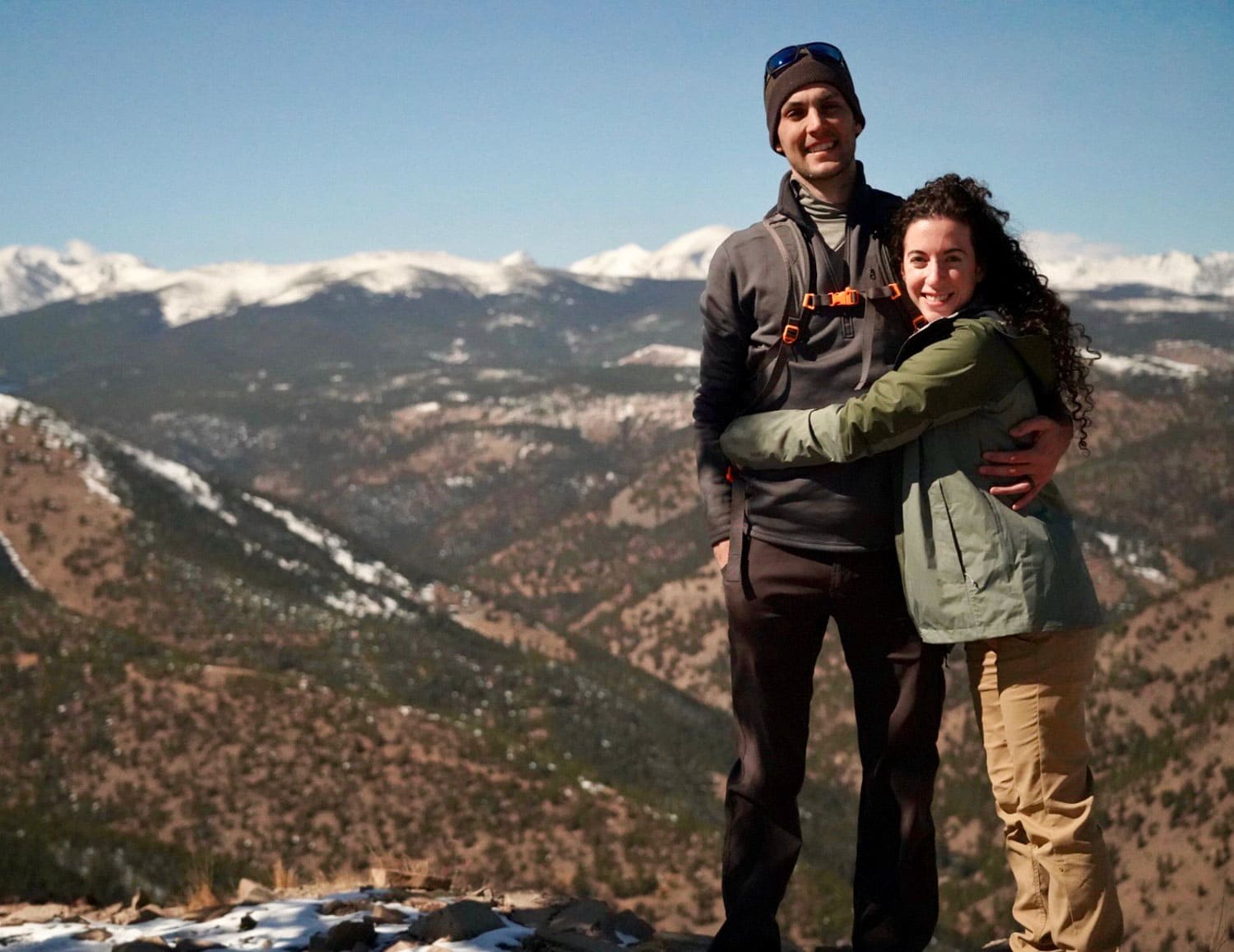 Man and woman hugging on top of a mountain